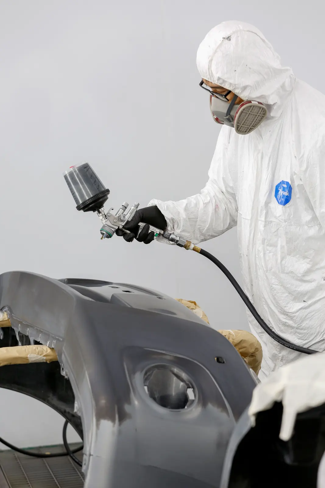 Painter in a booth preparing to refinish a panel